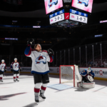 Avalanche player holds up jersey with Colorado logo while Flyers goalie slumps in background and scoreboard reads 3-2.
