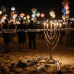 Broken menorah lies on Bondi Beach during a Hanukkah celebration with police tape and flashing lights.