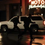 Two silhouettes flee from a white Chevy under neon-lit night with wet pavement reflections