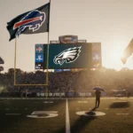 Rain-soaked flags flapping over football field at dusk with golden light and Eagles logo on scoreboard