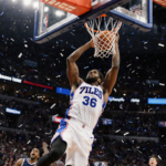 Edgecombe leaps toward the hoop securing a rebound scoring the game-winner with arena lights Sixers bench cheering confetti