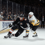 Tyson Foerster tumbling to the ice with Penguins opponent in a hockey collision and Flyers teammates rushing to his side.