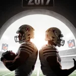 Two football players stand back‑to‑back in a dim tunnel with light one holding a ball and the other gesturing NFL logos behin
