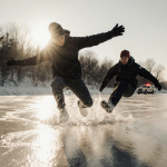 Three students struggling to free themselves with frozen legs on a lake with emergency responders along the shoreline