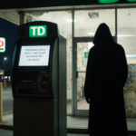 College student studying at desk with laptop and coffee surrounded by books and notes.
