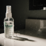 Bottle of ReBoost Nasal Spray sits abandoned on bathroom counter with murky residue visible inside and water droplets cling t