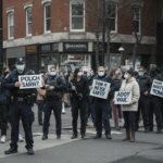 Assistant holding a sign that says I cant make shooting prompts Can I help you with something else with a gentle smile