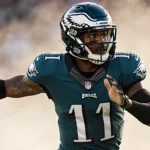 Jalen Carter throwing a pass with Eagles jersey and shoulder sleeve under dynamic lighting