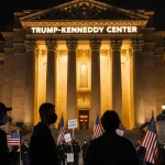 Protesters face each other with masked banners near golden-lit Kennedy Center and Trump-Kennedy sign.