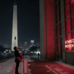 Musician holding guitar looks up at sign with Trump name on Kennedy Center façade with Washington Monument in snowy night