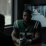 Kris Boyd sits in dim interrogation room with suspect cuffed across and TV flickering while winter chill outside window