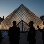 Security guards looking up at Louvre glass pyramid with clipboard and tense expression at dusk