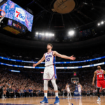 Luka Doncic raising arms with arena lights and screaming Sixers crowd