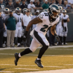 Marcus Epps safety tackling Charger receiver with focused eyes and extended arm in golden hour light