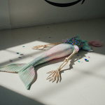 Mermaid costume lying abandoned on sterile white floor with faint Amazon logo in background