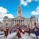 Revelers dancing near City Hall with ornate Mummers costumes and bright winter sky.