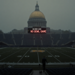 Figure walking away from field with foggy Notre Dame stadium and scoreboard reading No Bowl Game