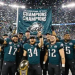 Eagles team holding championship trophy with confetti exploding around them and stadium lights shining bright