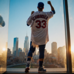 Kyle Schwarber stands triumphantly holding up a Phillies jersey with his name and number on it.