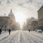 Pedestrians walking on freshly snow-covered Philadelphia street with the Liberty Bell under a pale blue sky