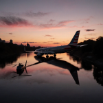 Two aircraft colliding over Potomac River with dusk sky reflections in water and silhouetted trees beside banks