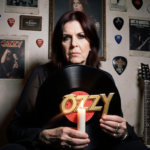 Sharon Osbourne holding an old vinyl record with candlelight and concert posters in the background