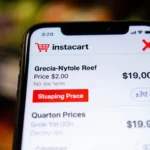 Smartphone screen showing varying Instacart prices with red highlights frustration and a blurred grocery shelf background