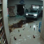 Surveillance camera records chaotic scene with shattered bottles and dark stain and a crushed Toyota Tacoma.