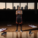 Terry Rozier standing on a basketball court at dusk with Miami Heat jerseys and sneakers on floor