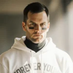 Tom Brady looks at camera with introspection and a white hoodie