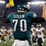 Tyler Steen Eagles football with 70 and arms up as referee hands him a yellow penalty card stadium lights shine