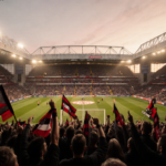 Fans wave red and black scarves with stadium floodlights and golden hour glow during Tyne Wear derby