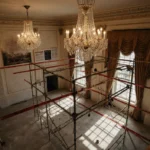 Aerial view of White House ballroom construction with half‑finished chandeliers and protest signs behind scaffolding.