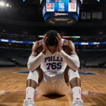 Philadelphia 76ers player sitting alone on court with head in hands and empty seats showing final score 116-110