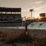 Skeletal Athens beach volleyball stadium standing with upright net and grass and Sarajevo winter track reflecting dusk light