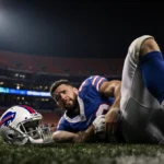 Bo Nix clutching ankle in pain with Buffalo Bills helmet visible and Denver Broncos stadium looming behind