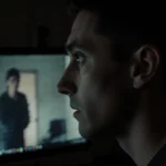 Person staring at pixelated video with shocked eyes and shadowy figure visible on screen