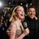 Elle Fanning holds microphone with Jack Black smiling beside her at glamorous red carpet event with flashing cameras behind