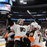 Philadelphia Flyers celebrating 2-1 victory with goalie raising arms and teammates huddled together