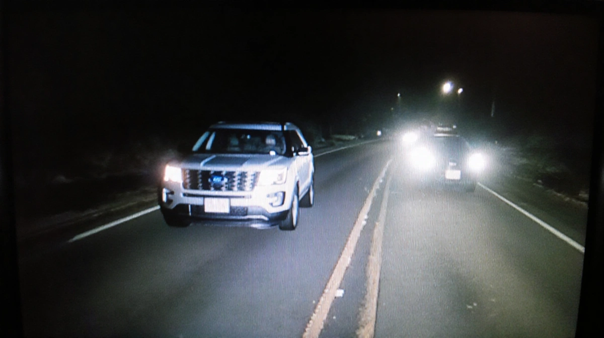 Ford Explorer driving west on Pitkin Avenue at night with headlights illuminating the road and approaching sedan visible in d