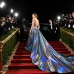 Actress walks down golden staircase in iridescent gown with cameras flashing at Beverly Hilton