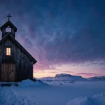 Greenland official stands near snow-covered church with Arctic sunset and frozen tundra stretching to sea