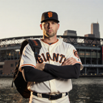 Harrison Bader standing with his baseball uniform near a glowing New York City stadium at sunset.