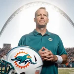 Jeff Hafley stands confidently with Miami Dolphins helmet and stadium fans behind him showing pride