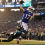 Josh Allen throwing touchdown pass while tackled with Bills fans cheering and golden hour lighting