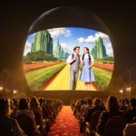Las Vegas Sphere screen projects Wizard of Oz scene with golden night glow and audience in luxurious vintage seats