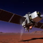 MAVEN Mars orbiter spinning in space with tilted solar panels and faint glow against a blue‑purple Martian sky.