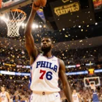 Tyrese Maxey celebrates with raised arm and confetti showering down while wearing his Philadelphia 76ers jersey with cheering