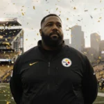 Mike Tomlin stands on Steelers sideline with confetti falling and Pittsburgh skyline behind