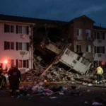 Emergency responders surround collapsed first floor of Silver Lake Nursing Home with debris and emergency lights at dusk